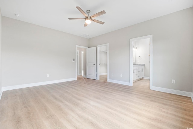1900 Blue Bird Rd, Loris, SC 29569 - unfurnished bedroom featuring a walk in closet, light wood-type flooring, ensuite bathroom, and ceiling fan
