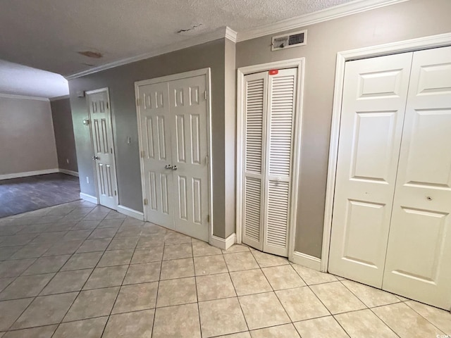 600 65th Ave N Unit 8, Myrtle Beach, SC 29572 - unfurnished bedroom featuring ornamental molding, multiple closets, light tile patterned floors, baseboards, and a textured ceiling