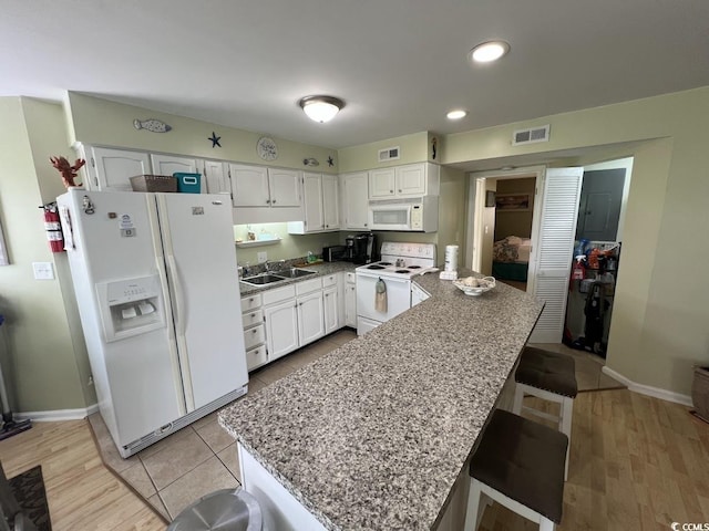 1101 Possum Trot Rd Unit A202, North Myrtle Beach, SC 29582 - kitchen featuring white appliances, white cabinets, a peninsula, a breakfast bar area, and recessed lighting