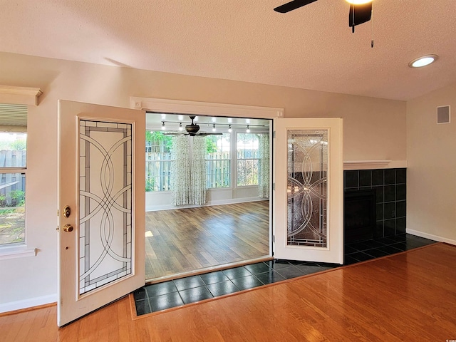 3904 Williamson Cir, Myrtle Beach, SC 29579 - entryway featuring wood finished floors, ceiling fan, baseboards, a textured ceiling, and a tiled fireplace