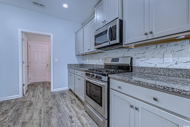 617 Chiswick Dr, Conway, SC 29526 - kitchen featuring stainless steel appliances, tasteful backsplash, light wood-style floors, baseboards, and dark stone countertops