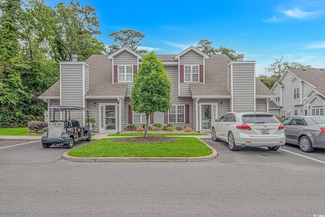 503 20th Ave N Unit 15B, North Myrtle Beach, SC 29582 - view of front of house with a chimney, a shingled roof, uncovered parking, and a front yard