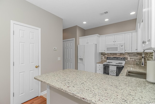 503 20th Ave N Unit 15B, North Myrtle Beach, SC 29582 - kitchen featuring white appliances, a peninsula, light stone counters, white cabinetry, and recessed lighting