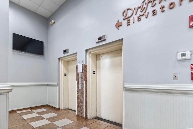 1207 S Ocean Blvd Unit 51001, Myrtle Beach, SC 29577 - corridor featuring elevator, a wainscoted wall, tile patterned flooring, and a high ceiling