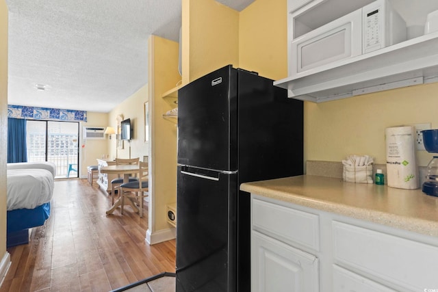1207 S Ocean Blvd Unit 51001, Myrtle Beach, SC 29577 - kitchen with freestanding refrigerator, a textured ceiling, light wood finished floors, white cabinetry, and light countertops