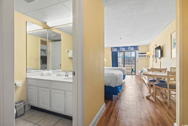 1207 S Ocean Blvd Unit 51001, Myrtle Beach, SC 29577 - bedroom featuring hardwood / wood-style flooring, a wall mounted AC, a textured ceiling, a sink, and baseboards