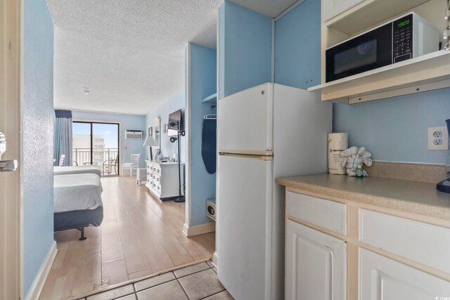 1207 S Ocean Blvd Unit 51312, Myrtle Beach, SC 29577 - kitchen with freestanding refrigerator, a textured ceiling, a wall mounted air conditioner, light countertops, and open shelves
