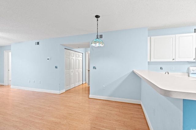 6016 Dick Pond Rd Unit 109, Myrtle Beach, SC 29588 - kitchen featuring light countertops, white cabinets, baseboards, light wood-style flooring, and a textured ceiling