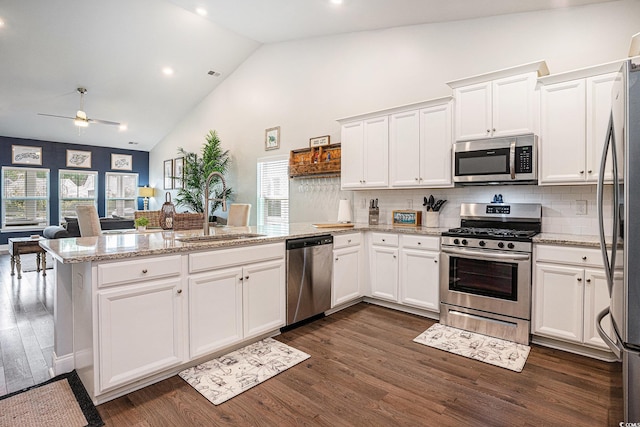 981 Mourning Dove Dr, Myrtle Beach, SC 29577 - kitchen featuring appliances with stainless steel finishes, a sink, a peninsula, white cabinetry, and high vaulted ceiling