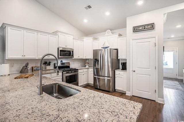 981 Mourning Dove Dr, Myrtle Beach, SC 29577 - kitchen featuring stainless steel appliances, light stone countertops, white cabinetry, tasteful backsplash, and lofted ceiling
