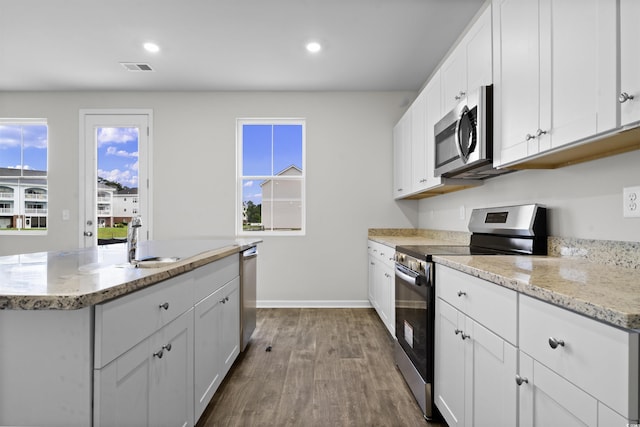435 Falling Leaf Loop, Myrtle Beach, SC 29588 - kitchen with stainless steel appliances, dark wood-style floors, white cabinets, a kitchen island with sink, and light stone counters