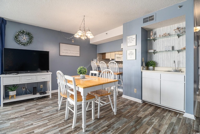 1425 S Ocean Blvd Unit 2A, North Myrtle Beach, SC 29582 - dining area featuring dark wood-style flooring, wet bar, a textured ceiling, a chandelier, and baseboards