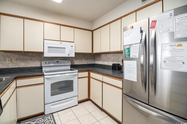 1425 S Ocean Blvd Unit 2A, North Myrtle Beach, SC 29582 - kitchen featuring white appliances, cream cabinetry, dark countertops, and light tile patterned floors