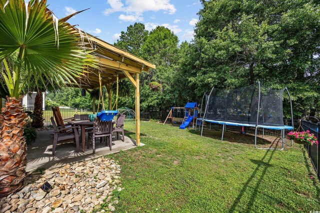 5149 Morning Frost Pl, Myrtle Beach, SC 29579 - view of yard featuring a trampoline, a playground, a patio, view of scattered trees, and outdoor dining area