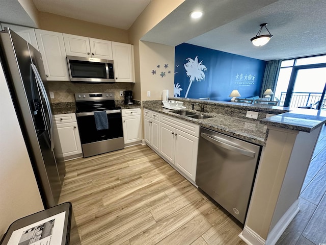 3000 N Ocean Blvd Unit 1406, Myrtle Beach, SC 29572 - kitchen with appliances with stainless steel finishes, a sink, a peninsula, light wood finished floors, and white cabinetry