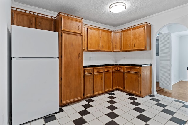 218 Waccamaw Village Dr Unit 218, Myrtle Beach, SC 29579 - kitchen featuring freestanding refrigerator, light floors, tile countertops, brown cabinets, and arched walkways