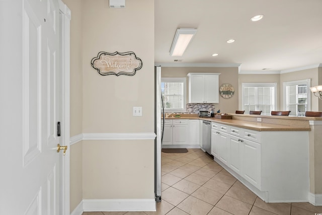 4890 Luster Leaf Cir Unit 201, Myrtle Beach, SC 29577 - kitchen with stainless steel dishwasher, a peninsula, white cabinetry, light tile patterned floors, and crown molding