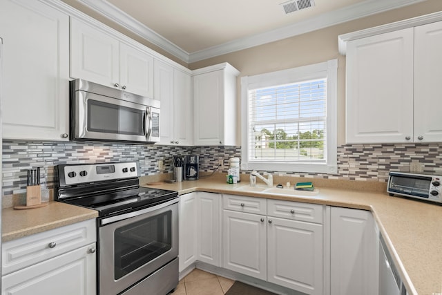 4890 Luster Leaf Cir Unit 201, Myrtle Beach, SC 29577 - kitchen with appliances with stainless steel finishes, crown molding, a sink, tasteful backsplash, and white cabinets