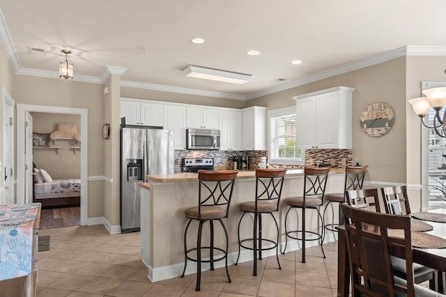 4890 Luster Leaf Cir Unit 201, Myrtle Beach, SC 29577 - kitchen with appliances with stainless steel finishes, a peninsula, decorative backsplash, white cabinetry, and light tile patterned floors