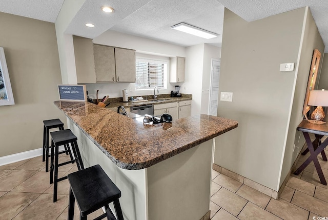 2511 S Ocean Blvd Unit 507G, Myrtle Beach, SC 29577 - kitchen with a sink, a textured ceiling, a breakfast bar area, light tile patterned floors, and a peninsula