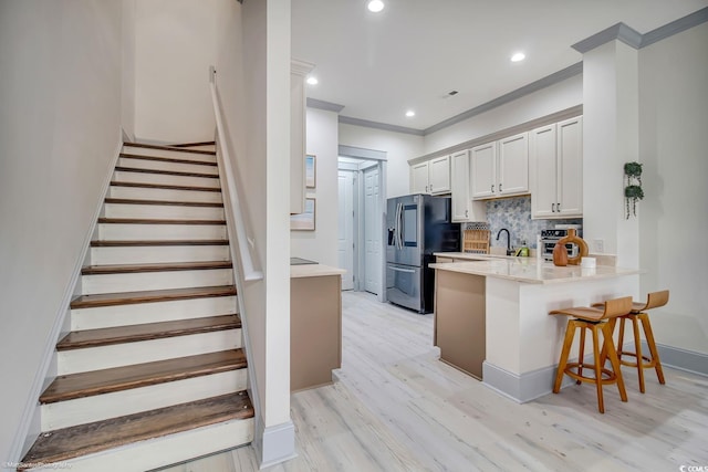 3477 Bristol Ln Unit 3477, Myrtle Beach, SC 29577 - kitchen featuring stainless steel fridge with ice dispenser, a peninsula, a breakfast bar, decorative backsplash, and light wood finished floors
