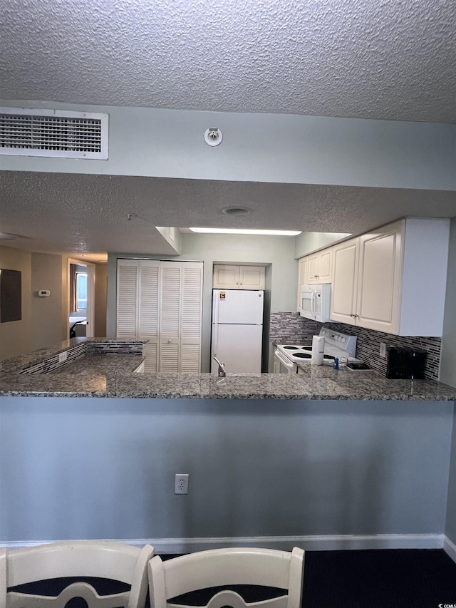 201 77th Ave N Unit 1133, Myrtle Beach, SC 29572 - kitchen with white appliances, a textured ceiling, dark stone counters, backsplash, and a peninsula