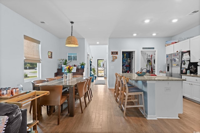 196 Cypress Tree Loop, Longs, SC 29568 - kitchen featuring stainless steel refrigerator with ice dispenser, light wood-style flooring, light stone countertops, an island with sink, and recessed lighting