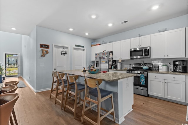 196 Cypress Tree Loop, Longs, SC 29568 - kitchen with appliances with stainless steel finishes, a kitchen island with sink, wood finished floors, light stone countertops, and recessed lighting