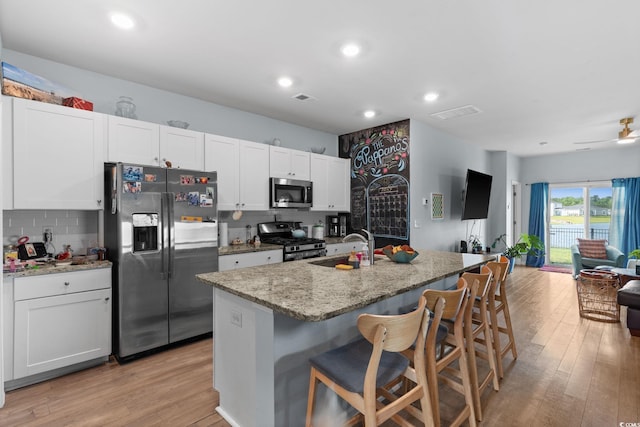 196 Cypress Tree Loop, Longs, SC 29568 - kitchen featuring appliances with stainless steel finishes, a sink, backsplash, open floor plan, and light wood-type flooring