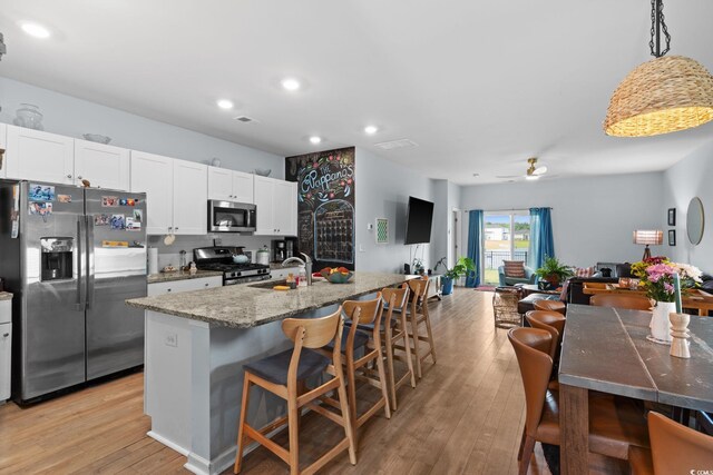 196 Cypress Tree Loop, Longs, SC 29568 - kitchen featuring stainless steel appliances, a sink, a kitchen breakfast bar, white cabinets, and light wood-style floors