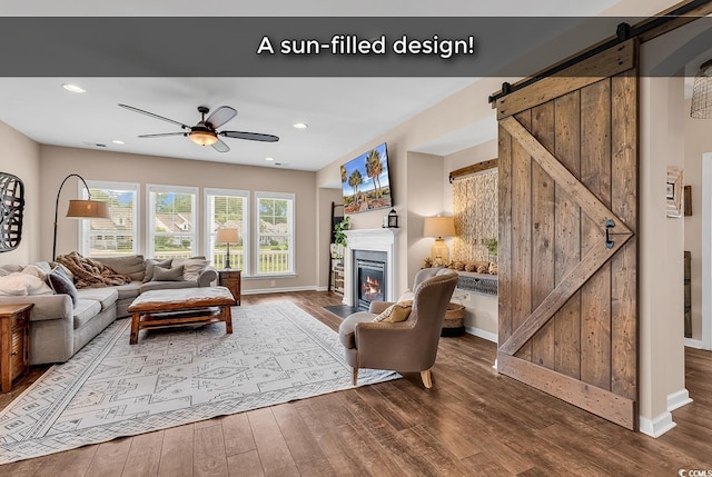1227 Cypress Shadow Ct, Murrells Inlet, SC 29576 - living area with a barn door, dark wood-style flooring, ceiling fan, a glass covered fireplace, and baseboards