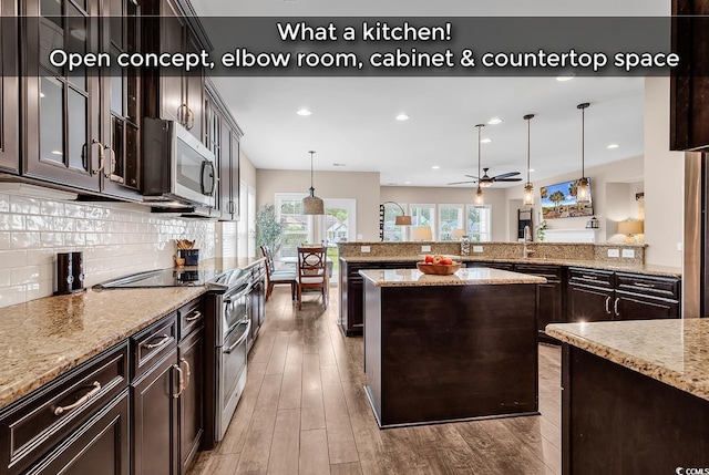 1227 Cypress Shadow Ct, Murrells Inlet, SC 29576 - kitchen featuring appliances with stainless steel finishes, wood finished floors, hanging light fixtures, dark brown cabinetry, and tasteful backsplash