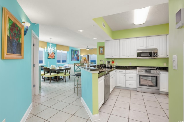 5700 N Ocean Blvd Unit Ph12, North Myrtle Beach, SC 29582 - kitchen with stainless steel appliances, a sink, a peninsula, dark countertops, and white cabinetry