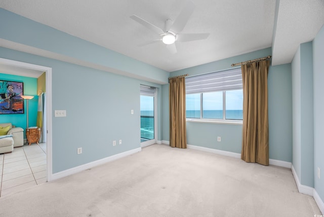 5700 N Ocean Blvd Unit Ph12, North Myrtle Beach, SC 29582 - spare room with carpet flooring, a ceiling fan, a water view, baseboards, and a textured ceiling