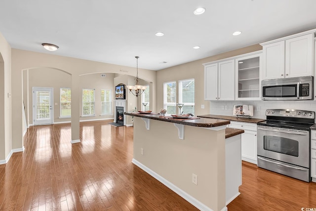 126 Dreamland Dr, Murrells Inlet, SC 29576 - kitchen featuring stainless steel appliances, a breakfast bar area, open floor plan, glass insert cabinets, and arched walkways
