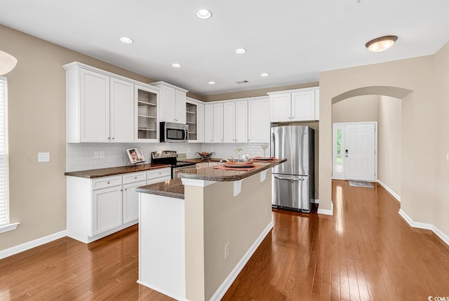 126 Dreamland Dr, Murrells Inlet, SC 29576 - kitchen with appliances with stainless steel finishes, dark wood-style flooring, backsplash, glass insert cabinets, and white cabinetry