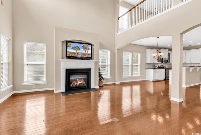 126 Dreamland Dr, Murrells Inlet, SC 29576 - unfurnished living room featuring a high ceiling, a chandelier, wood finished floors, a glass covered fireplace, and baseboards