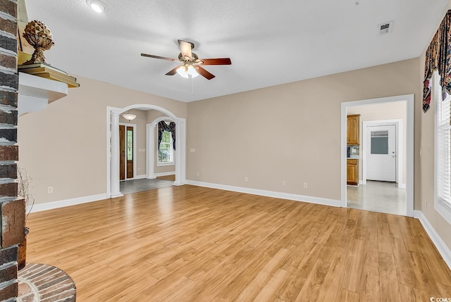 6161 Inman Cir, Conway, SC 29526 - unfurnished living room with ceiling fan, arched walkways, light wood-style flooring, baseboards, and ornate columns