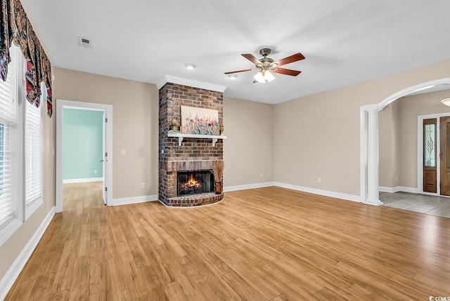 6161 Inman Cir, Conway, SC 29526 - unfurnished living room featuring arched walkways, light wood-style flooring, and a brick fireplace