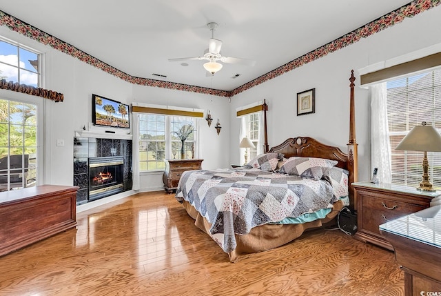 383 Oatland Lake Rd, Pawleys Island, SC 29585 - bedroom with light wood finished floors, a fireplace, and ceiling fan