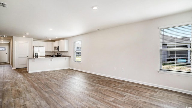575 Strawberry Field Way, Galivants Ferry, SC 29544 - kitchen featuring appliances with stainless steel finishes, wood finished floors, a kitchen breakfast bar, white cabinets, and a peninsula