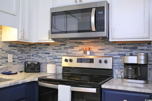 5601 N Ocean Blvd Unit A-307, Myrtle Beach, SC 29577 - kitchen with appliances with stainless steel finishes, blue cabinets, white cabinetry, backsplash, and light stone counters