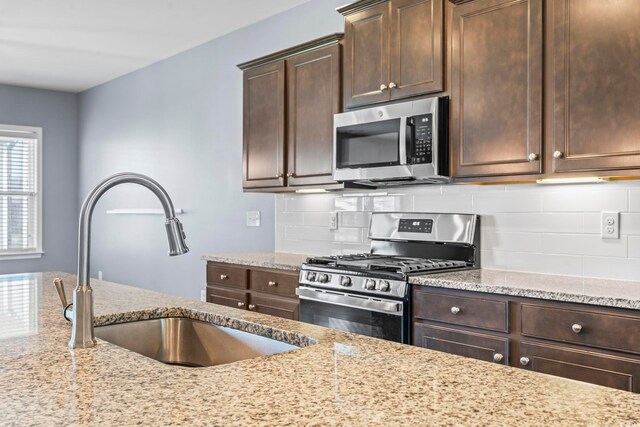 4115 Alvina Way, Myrtle Beach, SC 29579 - kitchen featuring stainless steel appliances, a sink, light stone counters, dark brown cabinetry, and backsplash
