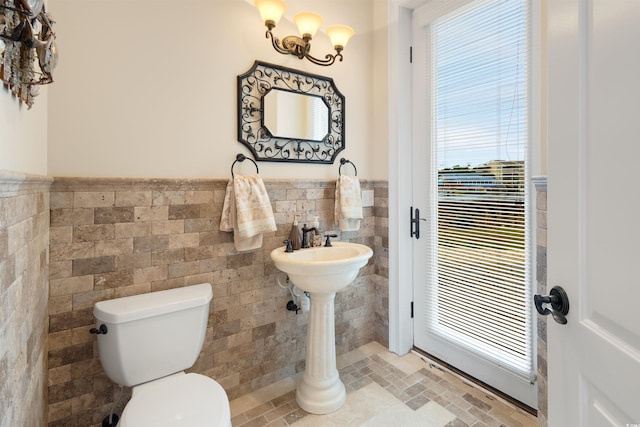 2715 Ships Wheel Dr, North Myrtle Beach, SC 29582 - half bathroom featuring tile walls, toilet, a wainscoted wall, stone finish floors, and plenty of natural light