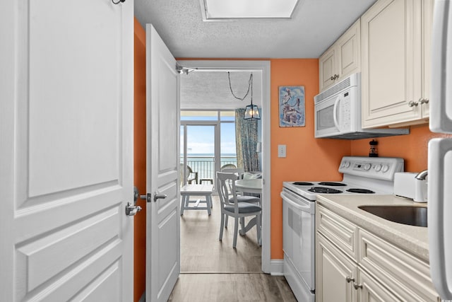 2801 S Ocean Blvd Unit 835, North Myrtle Beach, SC 29582 - kitchen with white appliances, light wood-style flooring, light countertops, a water view, and a textured ceiling
