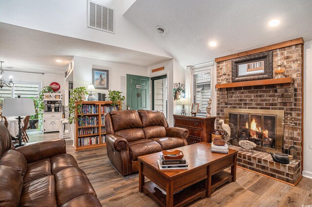 705 11th Ave S, North Myrtle Beach, SC 29582 - living area with a textured ceiling, plenty of natural light, a brick fireplace, wood finished floors, and vaulted ceiling