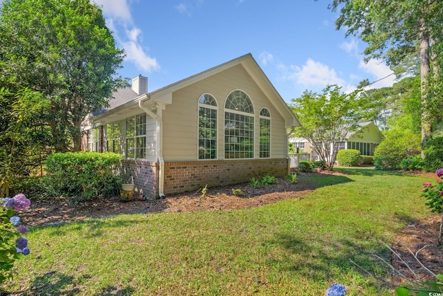 168 Mackinley Cir, Pawleys Island, SC 29585 - view of property exterior featuring brick siding, a chimney, and a lawn