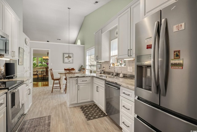 168 Mackinley Cir, Pawleys Island, SC 29585 - kitchen with stainless steel appliances, light wood-style flooring, white cabinetry, tasteful backsplash, and a peninsula