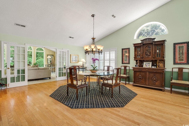 168 Mackinley Cir, Pawleys Island, SC 29585 - dining area with french doors, a chandelier, light wood-style floors, and high vaulted ceiling