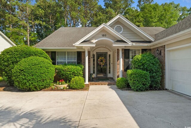 168 Mackinley Cir, Pawleys Island, SC 29585 - doorway to property with brick siding, driveway, a shingled roof, and an attached garage